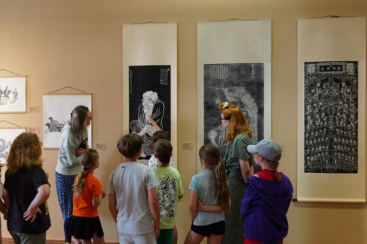 Mehrere Kinder bestaunen die ausgehangene Druckkunst in einer Galerie.