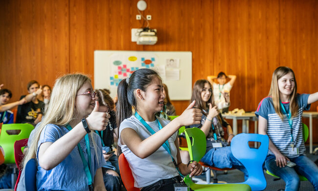 Schüler:innen in einem Klassenraum machen Daumen nach oben