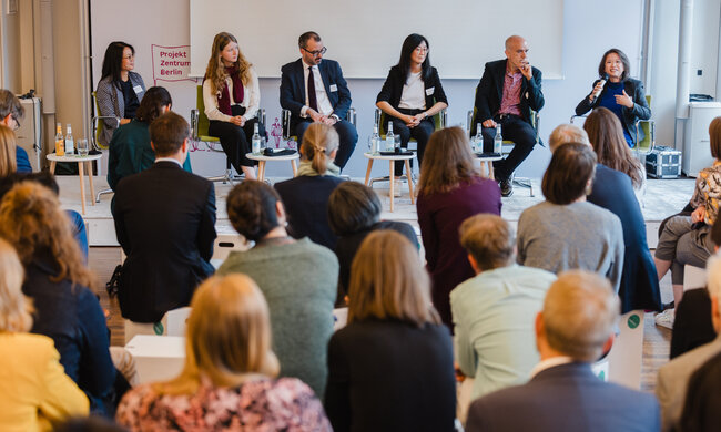 Ein Publikum sitzt vor einer Podiumsdiskussion