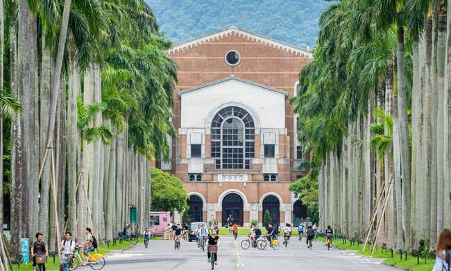 Zu sehen ist der Campus einer taiwanischen Universität. Menschen fahren Fahrrad