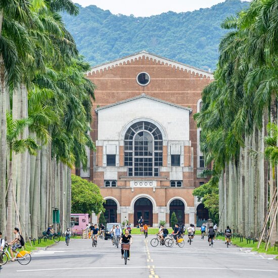 Zu sehen ist der Campus einer taiwanischen Universität. Menschen fahren Fahrrad