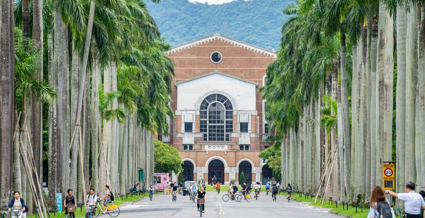 Zu sehen ist der Campus einer taiwanischen Universität. Menschen fahren Fahrrad