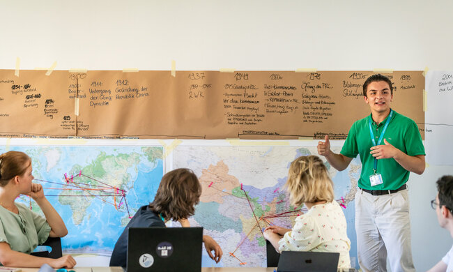 Ein Schüler steht vor einem Zeitstrahl und referiert zur Klasse
