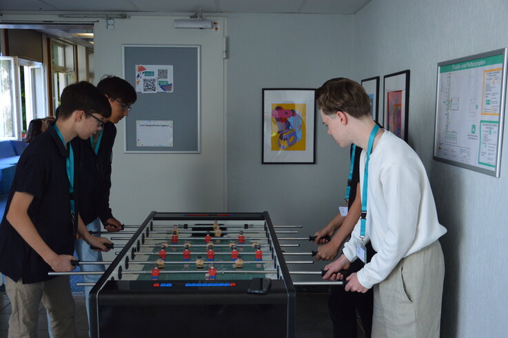 Drei Schüler:innen spielen Tischkicker
